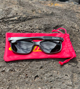 Tamba Sunglasses (Matte Black) sitting on a rock - rear view of sunglass arms folded in with logos showing.